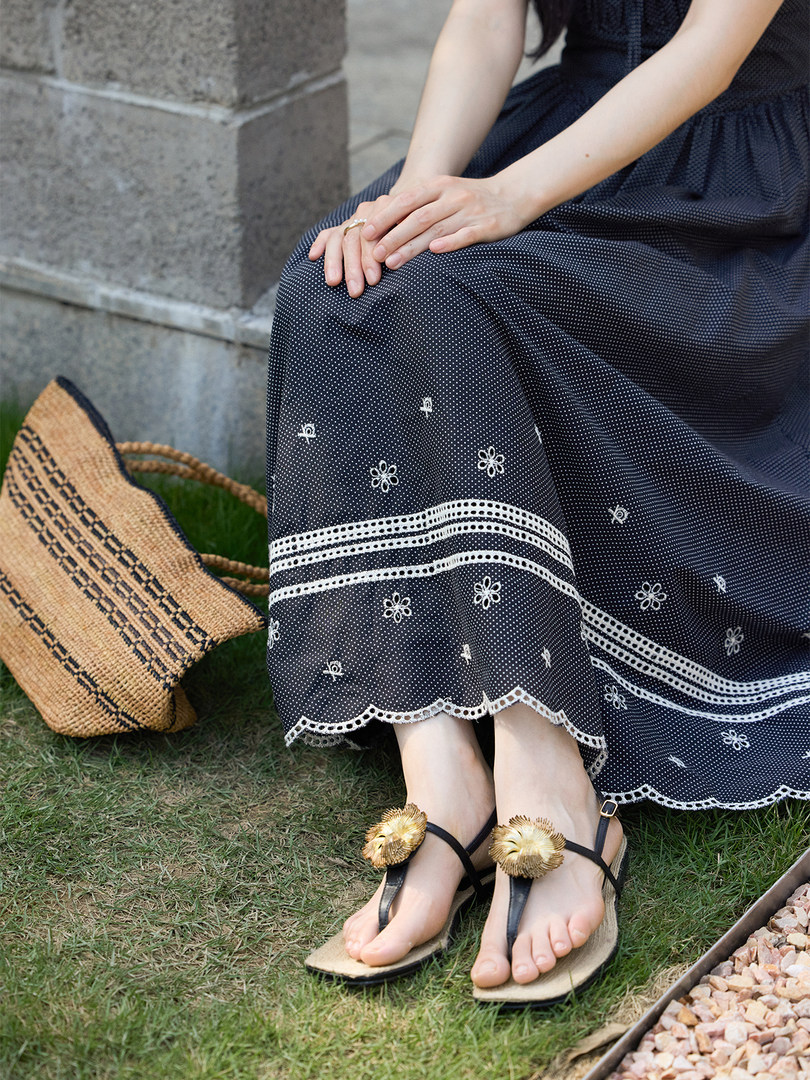 Woman wearing a black patterned dress and flat sandals outdoors