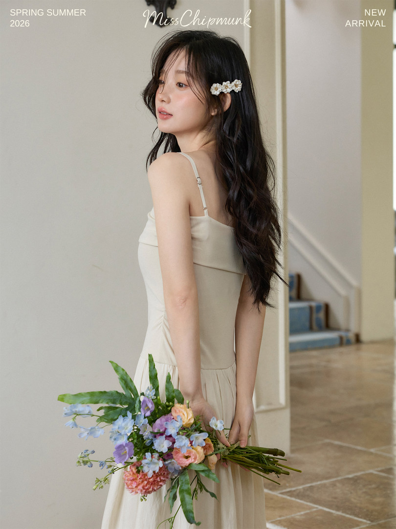 Woman wearing a beige spaghetti-strap dress holding a bouquet of flowers