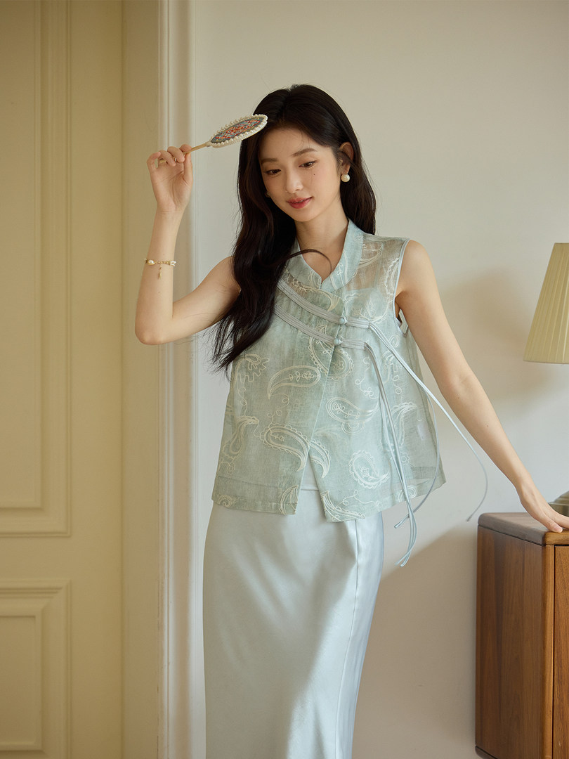 Model wearing a light blue sleeveless embroidered top with a long skirt