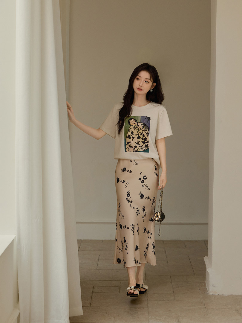Woman wearing a cream graphic T-shirt and beige floral midi skirt