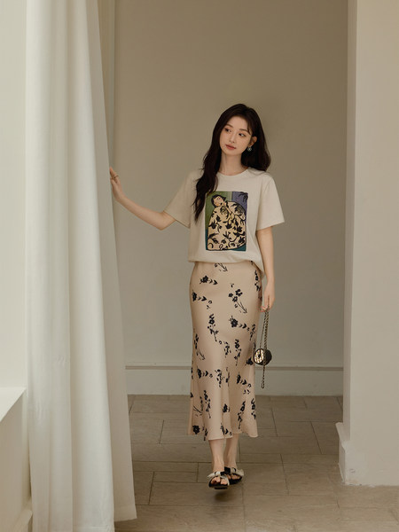 Woman wearing a cream graphic T-shirt and beige floral midi skirt