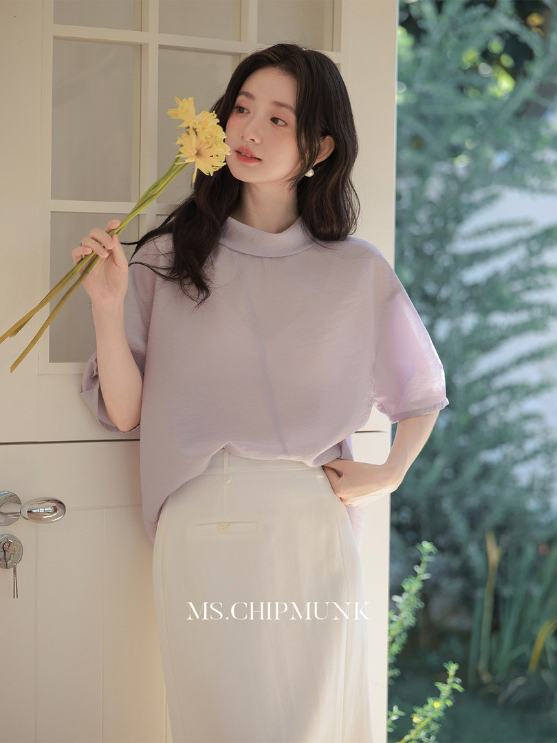 Woman wearing a light lavender short-sleeve blouse and cream trousers