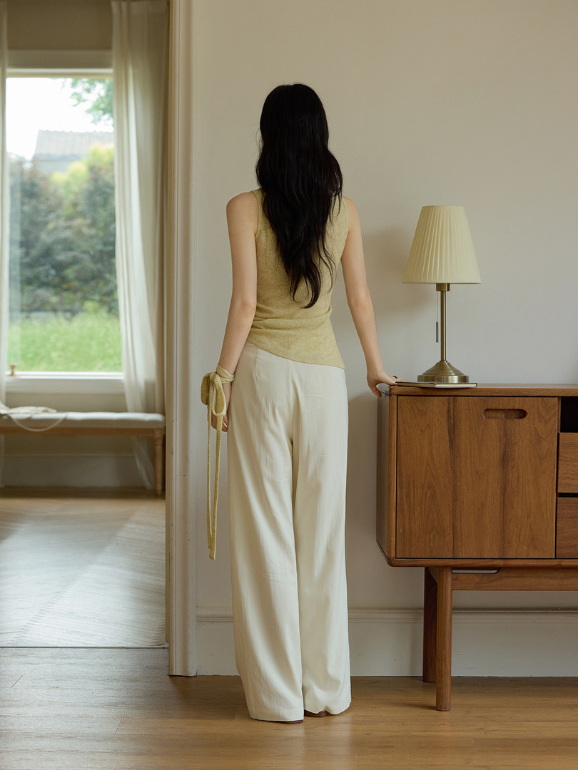 Woman wearing a sleeveless beige top and cream wide-leg pants indoors