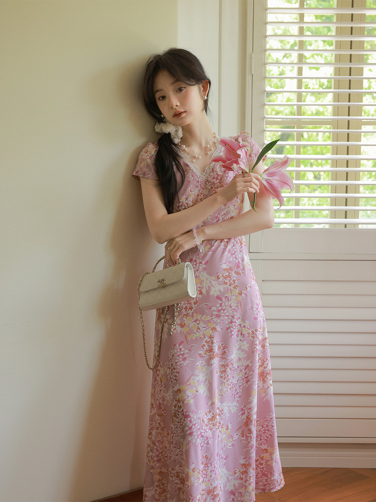 Woman wearing a pink floral dress and holding a small handbag