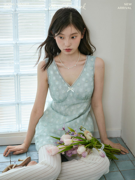 Model wearing a light blue sleeveless floral dress with lace trim