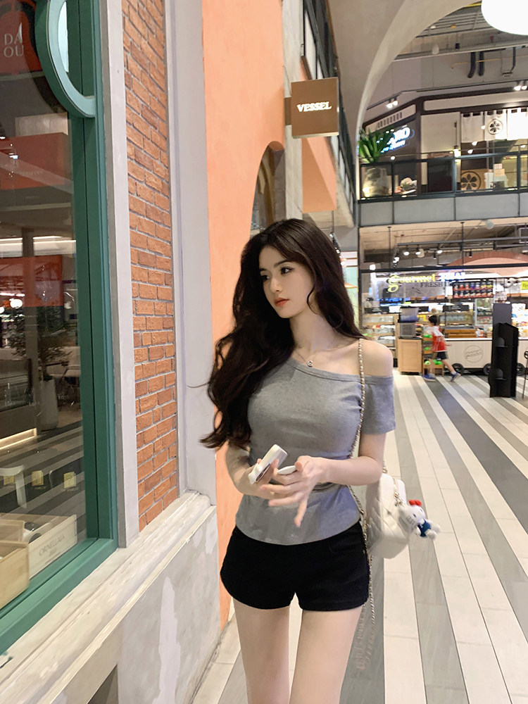 Woman wearing gray off-shoulder top and black shorts in a shopping mall