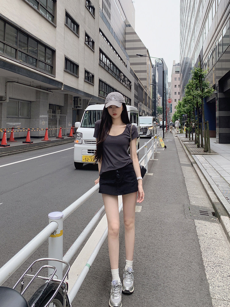 Woman wearing a gray top, black shorts, and sneakers on a city street