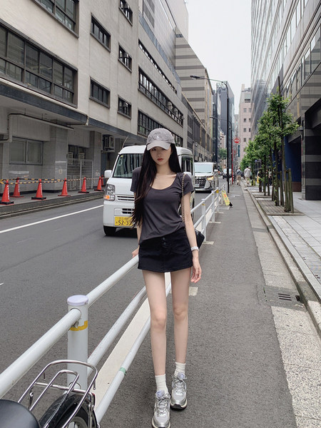 Woman wearing a gray top, black shorts, and sneakers on a city street