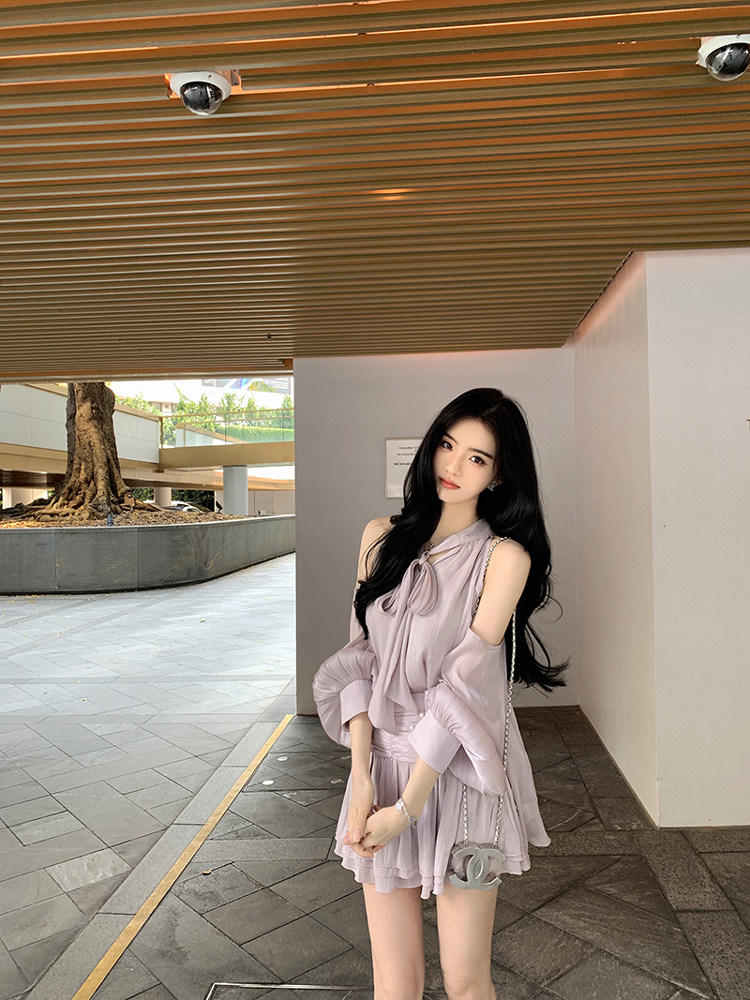 Woman wearing a light purple off-shoulder dress with ruffles, standing outdoors.