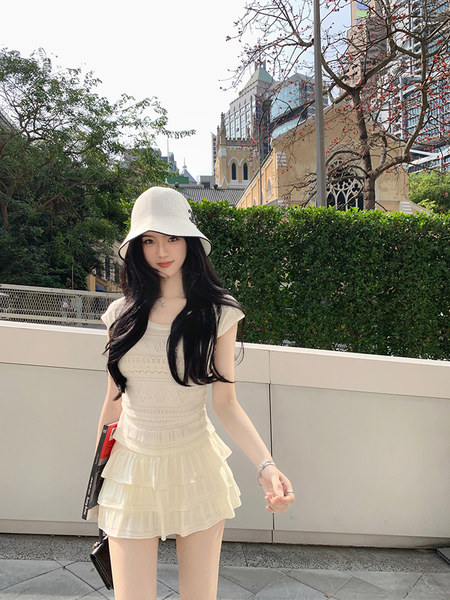 Woman wearing a white ruffled dress and bucket hat outdoors