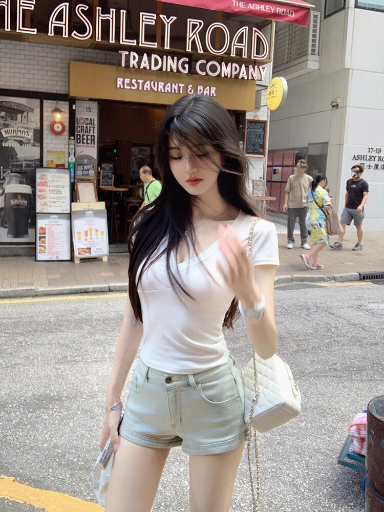 Woman wearing white V-neck t-shirt and light denim shorts on a city street