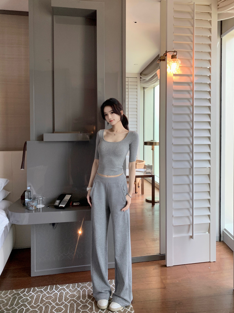Woman wearing a gray cropped top and matching wide-leg pants in a modern room setting