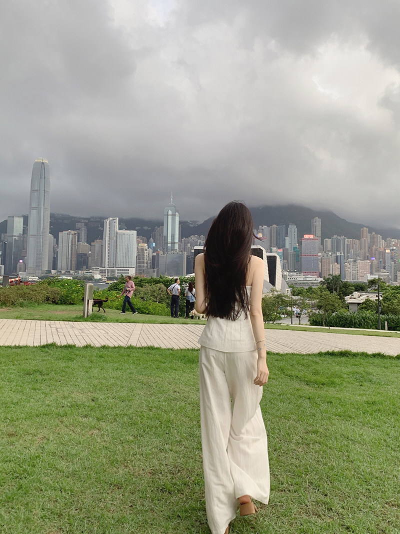 Woman wearing white outfit standing on grass with city skyline in background