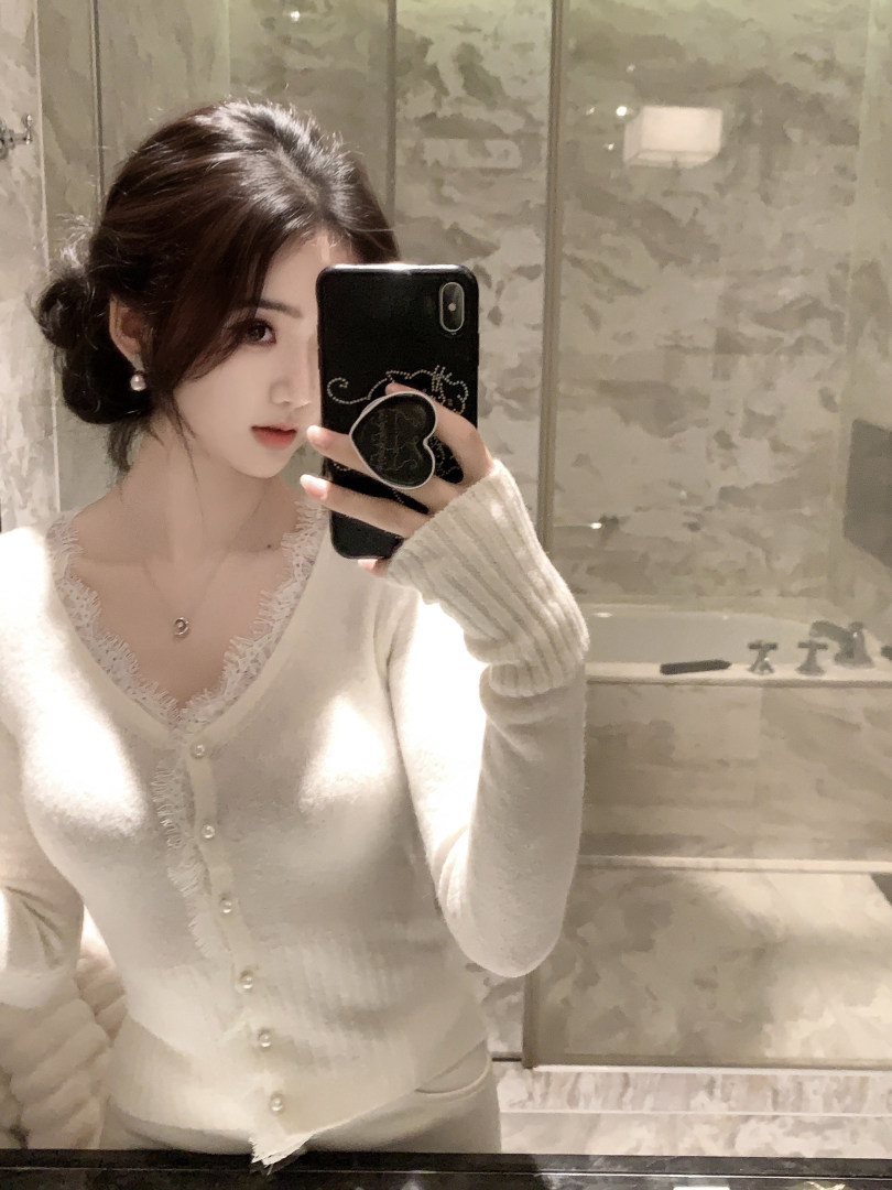 Woman taking mirror selfie wearing a white lace-trim cardigan