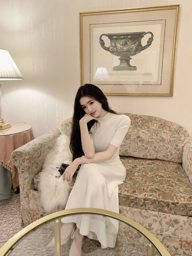 Woman wearing a white dress sitting on a floral couch