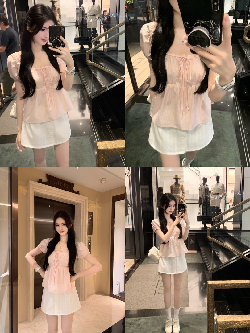 Woman taking mirror selfies wearing a light pink puff-sleeve top and white shorts in a luxury mall setting.