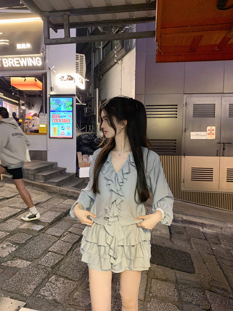 Woman wearing a light blue ruffled dress on a city street at night