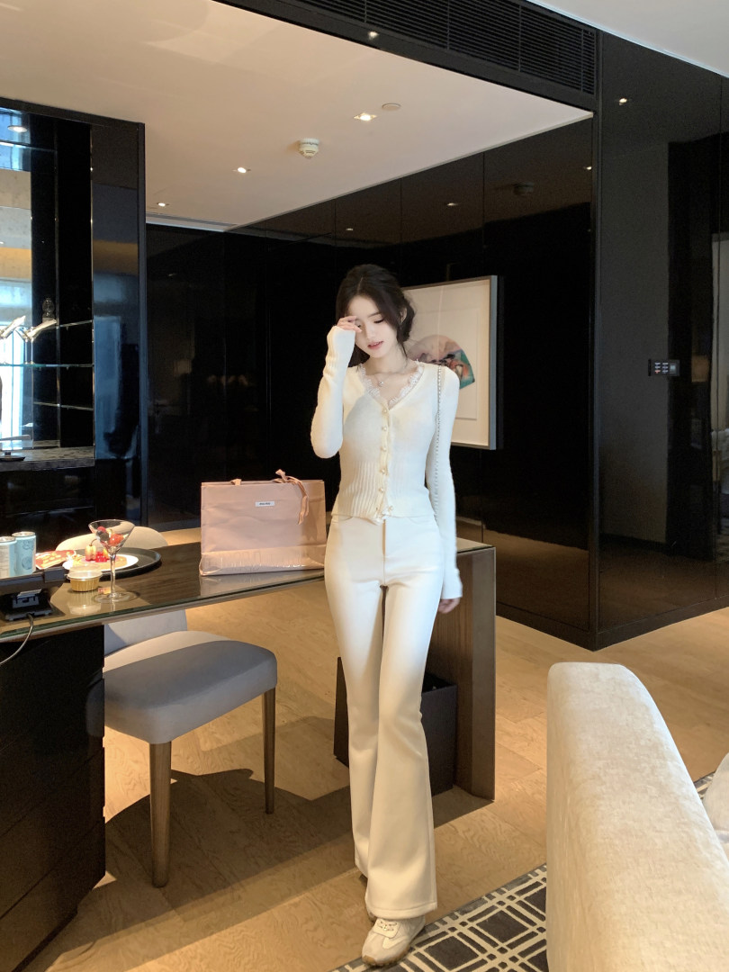 Woman wearing a white knit cardigan and matching pants in a modern interior setting