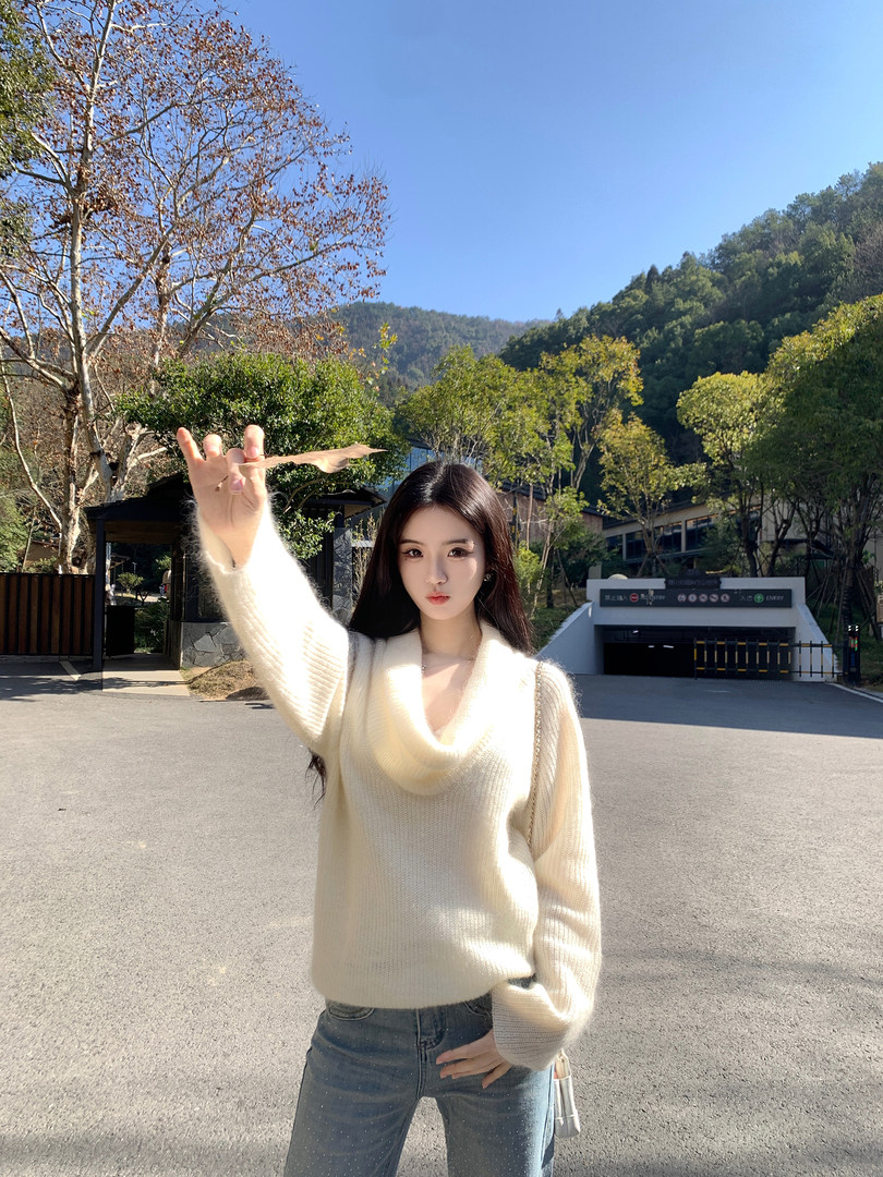 Woman wearing a cream-colored knit sweater outdoors with trees and hills in the background