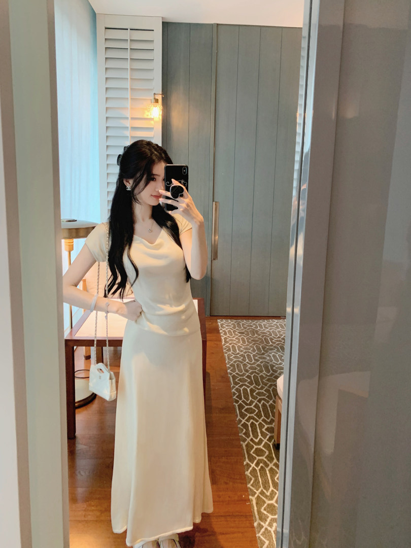 Woman taking mirror selfie wearing a cream-colored dress