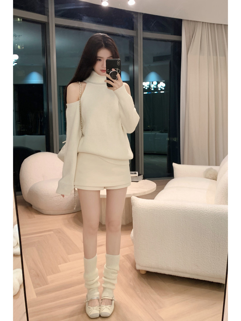 Woman wearing a white knit sweater and matching skirt with knee-high socks and bow flats, taking a mirror selfie.
