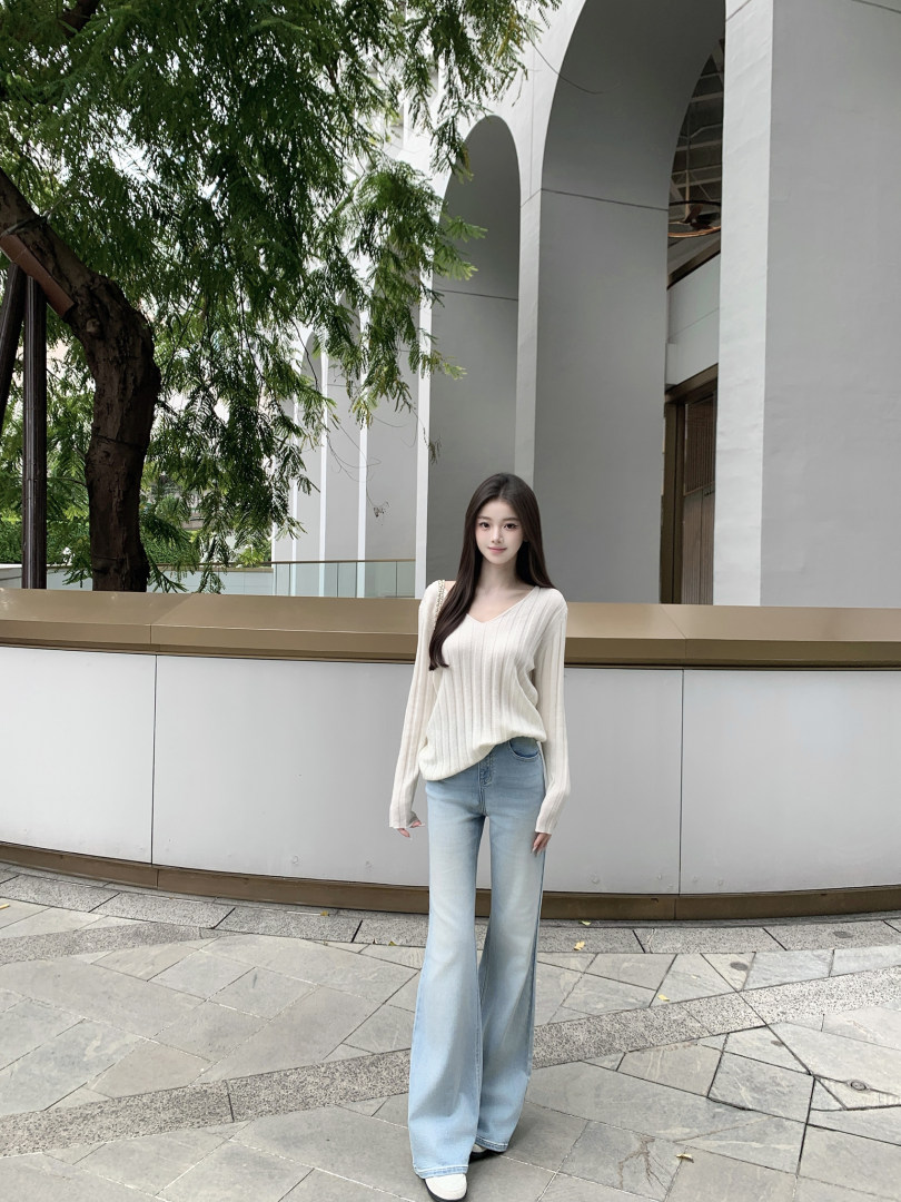 Woman wearing a cream ribbed sweater and light blue wide-leg jeans outdoors