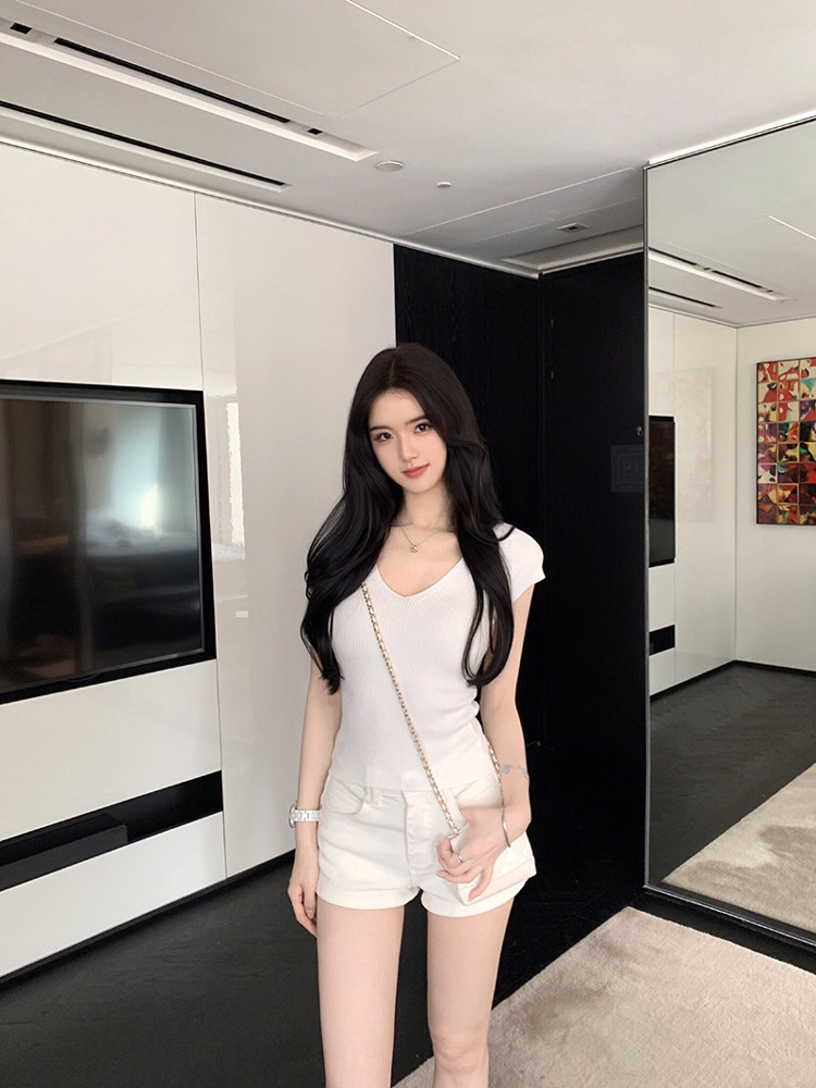 Woman wearing white ribbed top and white shorts in modern interior