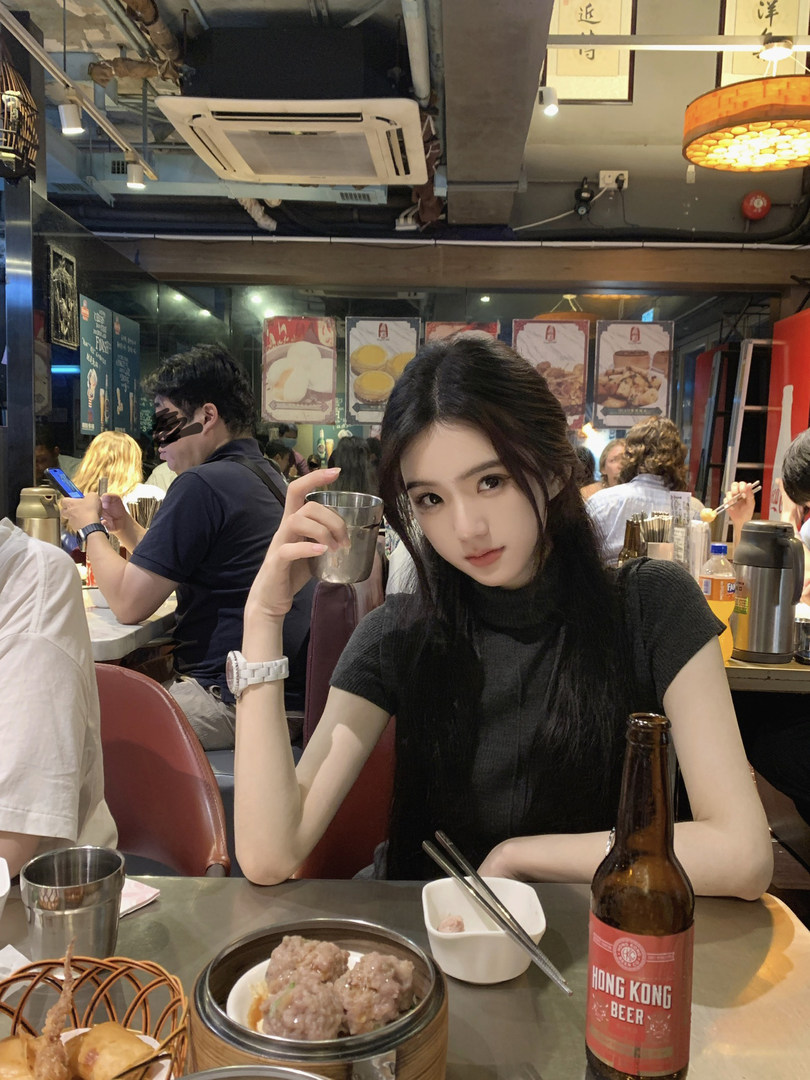 Woman wearing black top in restaurant setting with food and beer on table