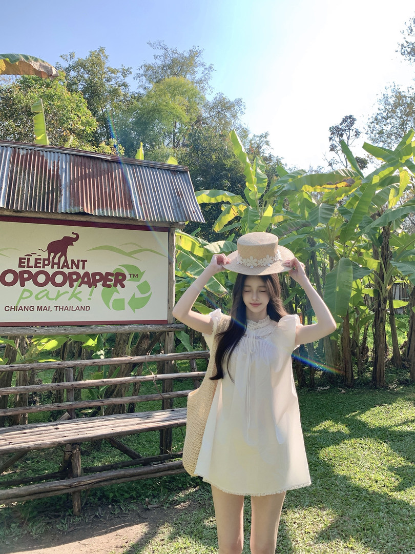 Woman wearing a white dress and straw hat outdoors in a tropical setting