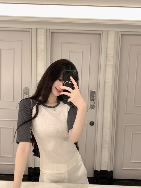 Woman taking mirror selfie wearing a gray and white raglan t-shirt