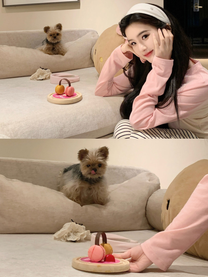 Woman wearing pink long-sleeve top and striped pants posing with a small dog on a couch