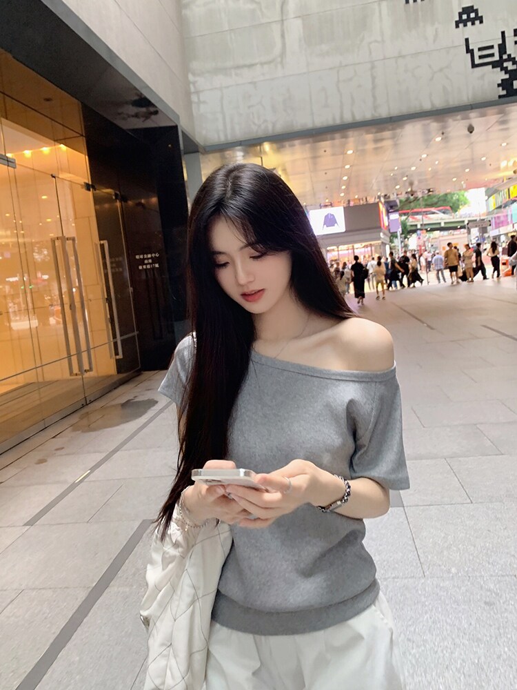 Woman wearing gray off-shoulder top in urban setting