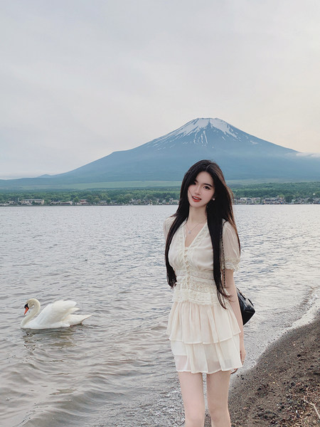 Woman wearing a white dress by a lake with a mountain in the background