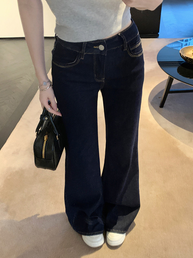 Model wearing dark blue wide-leg jeans with white sneakers and holding a black handbag