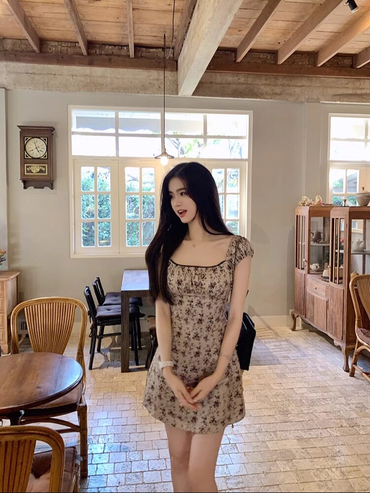 Woman wearing a floral mini dress in a rustic indoor setting