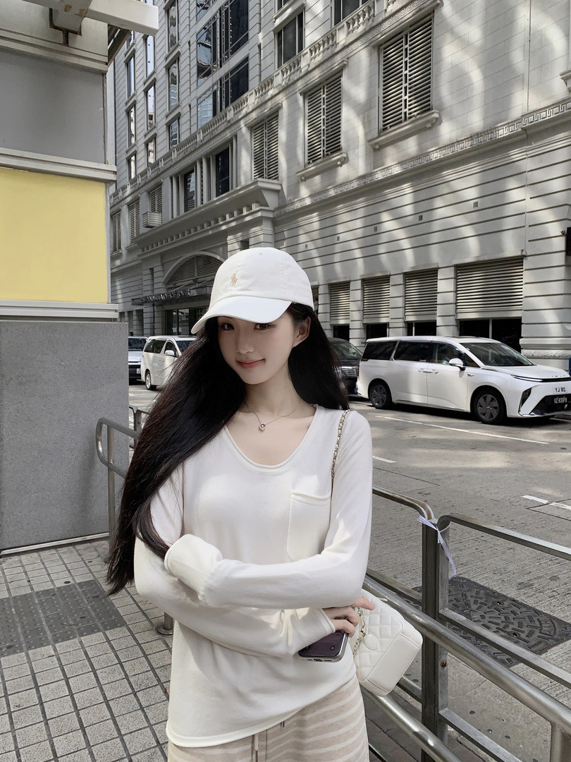 Woman wearing white long-sleeve top and white cap on city street