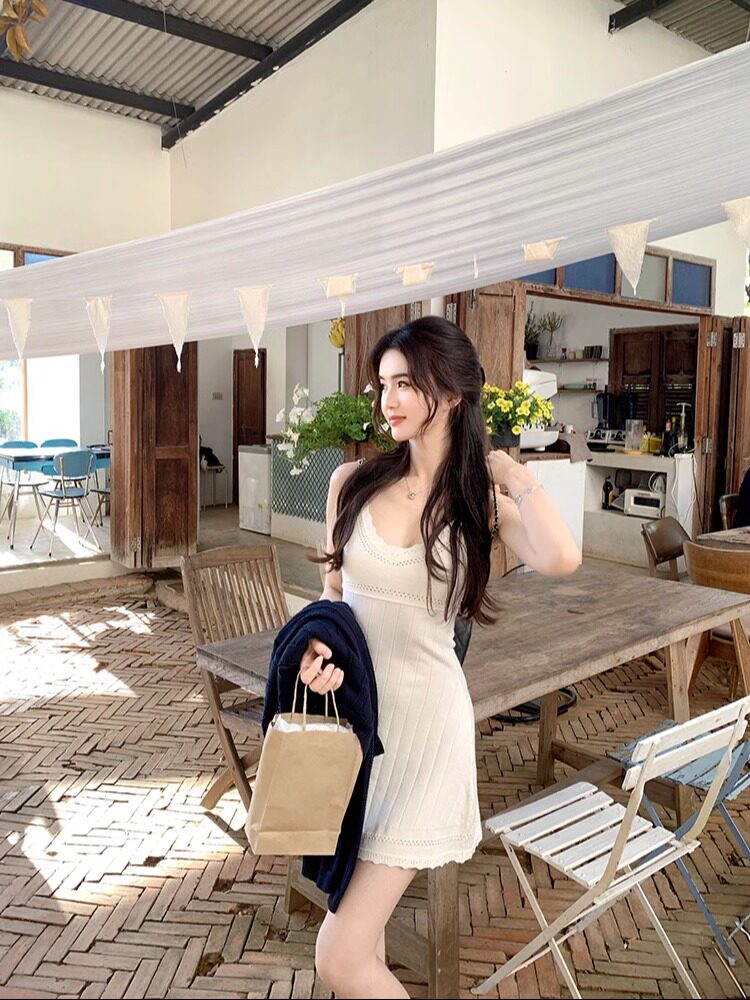Woman wearing a white ribbed knit dress in a rustic indoor setting
