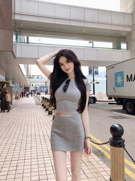 Woman wearing gray crop top and matching mini skirt outdoors