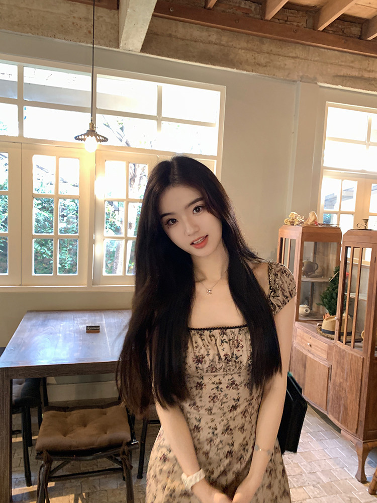 Woman wearing a floral print dress in a rustic indoor setting