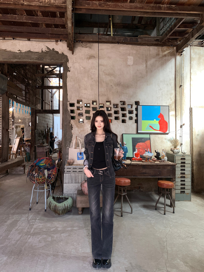 Woman wearing black denim jacket and jeans in a rustic indoor setting
