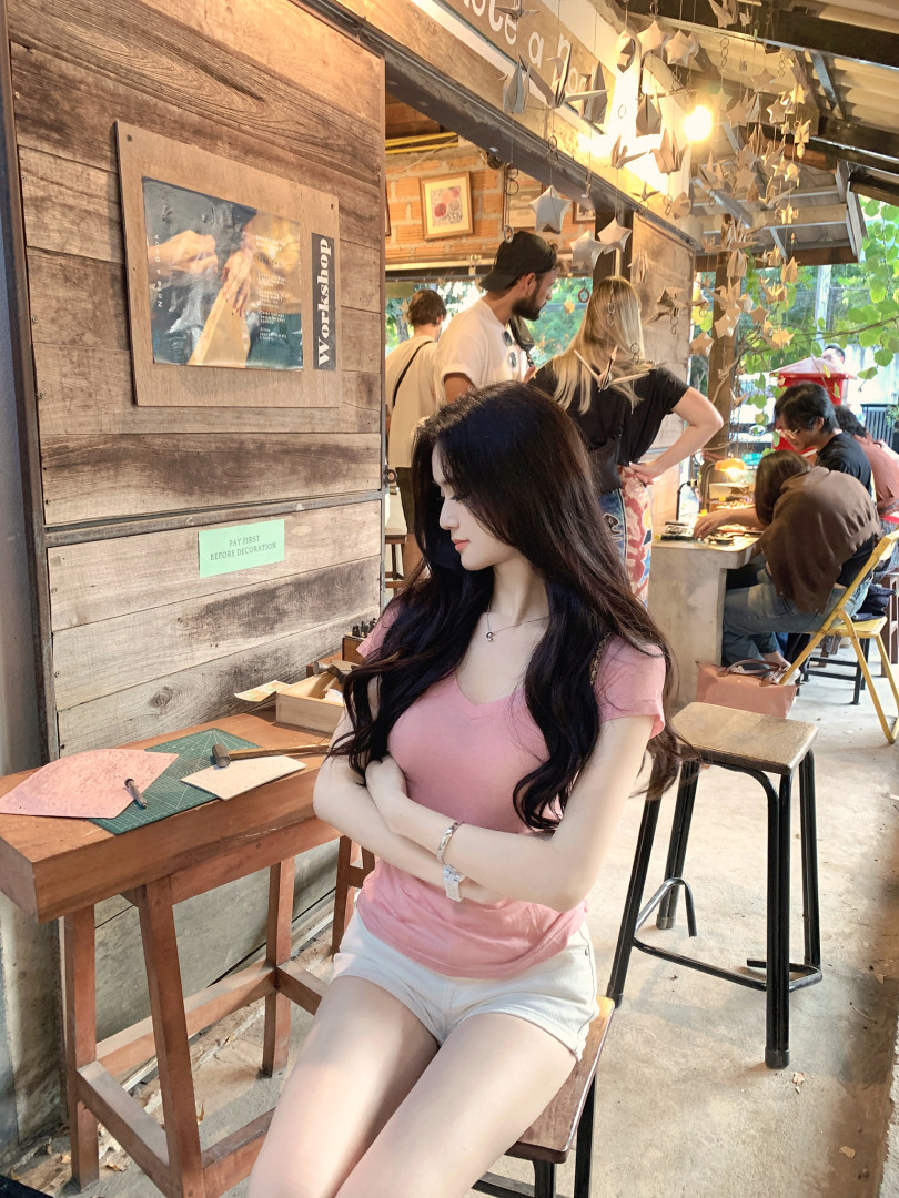Woman wearing pink V-neck T-shirt and white shorts sitting in a workshop setting