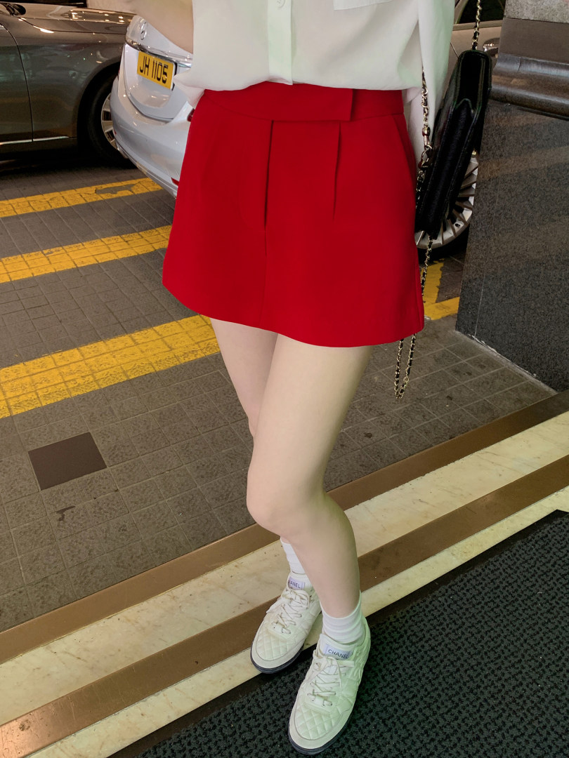 Model wearing red pleated mini skirt with white blouse and sneakers