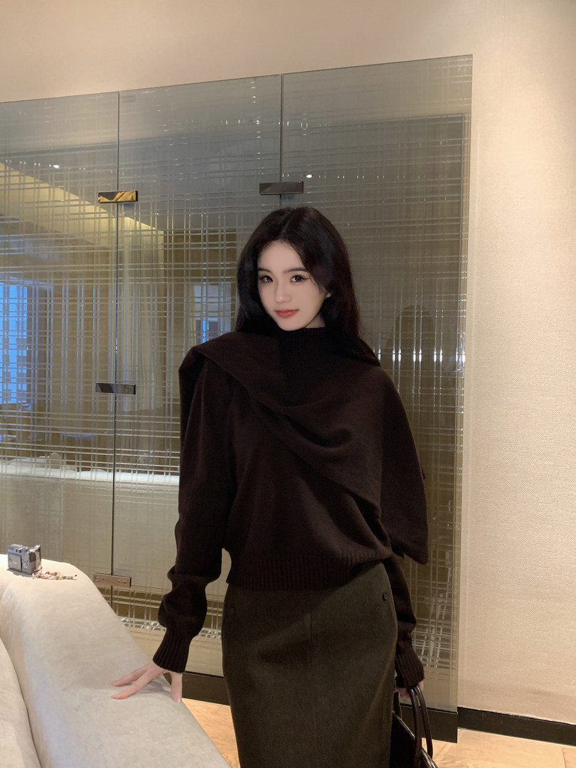 Woman wearing a dark brown draped sweater and olive skirt, posing indoors