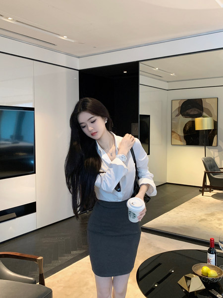 Woman wearing white blouse and black pencil skirt holding coffee cup