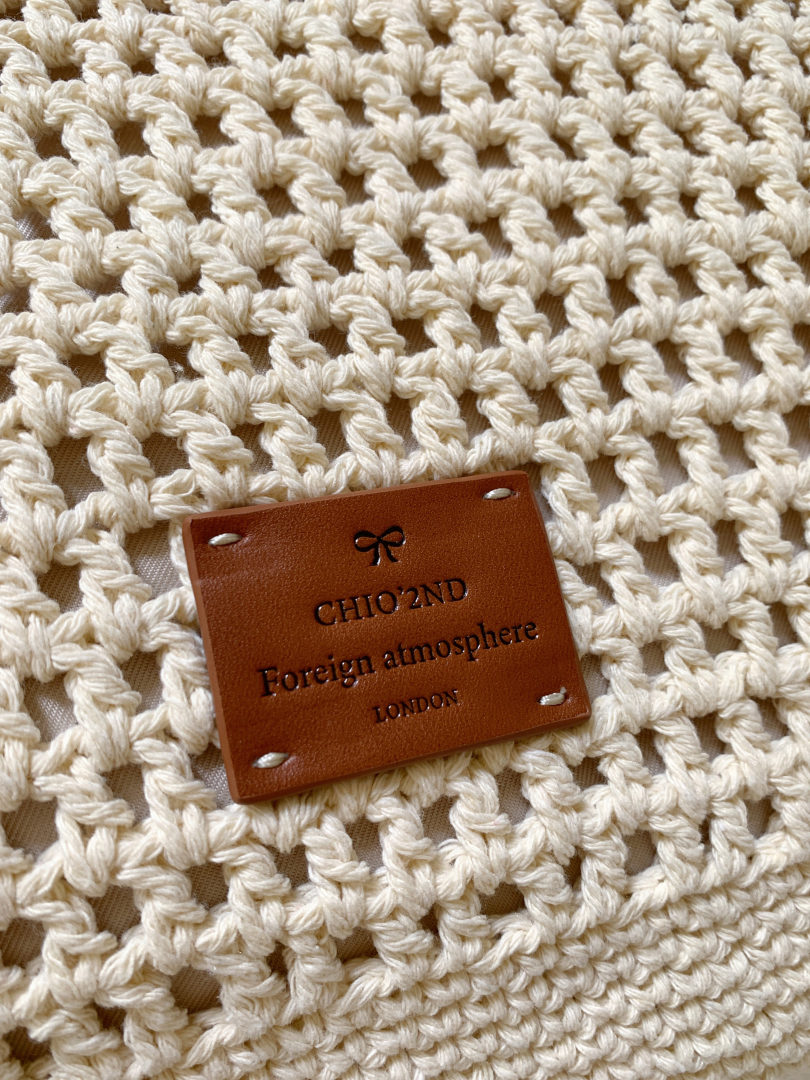 Cream crochet-textured product with a brown leather brand tag