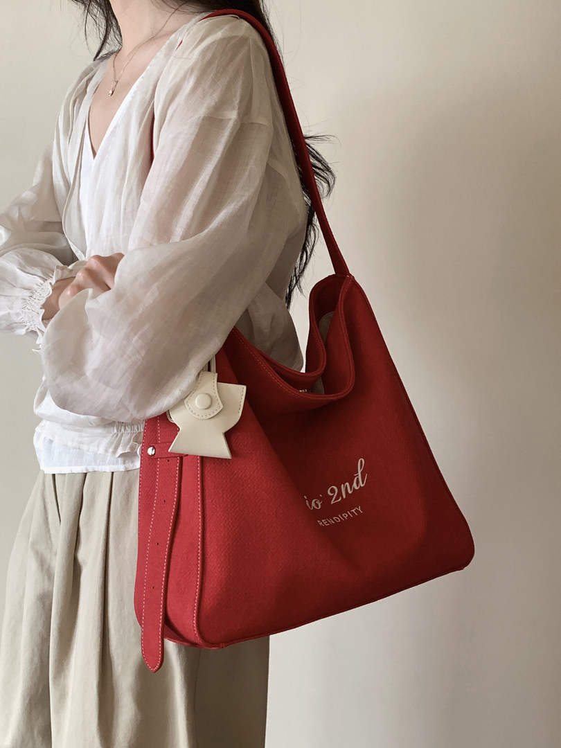 Woman wearing a large red tote shoulder bag with a white blouse and skirt