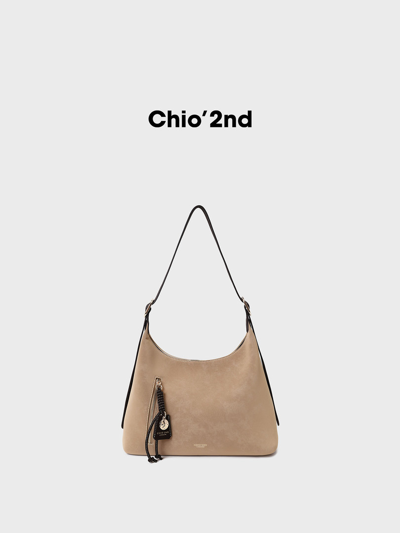 Beige shoulder handbag with black strap and front zipper charm on a plain background