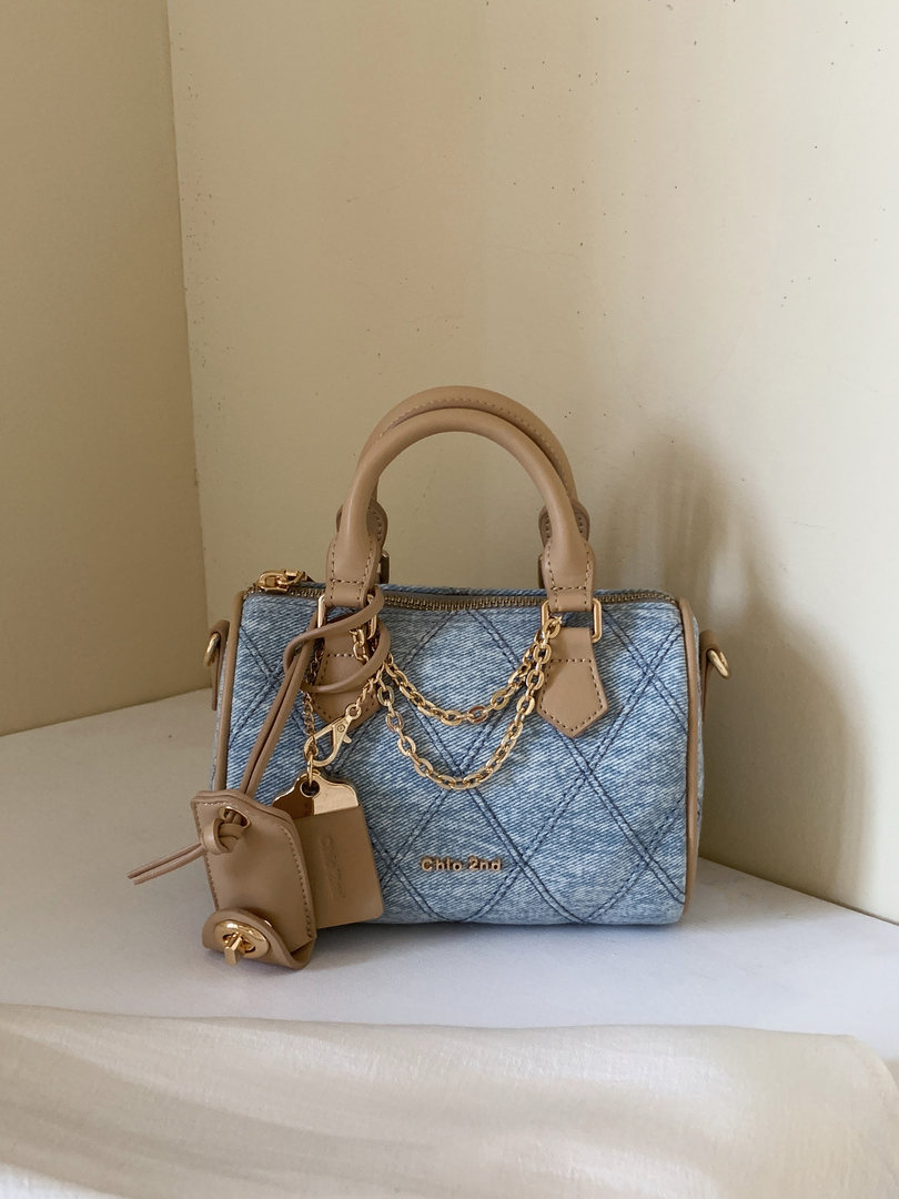 Blue denim handbag with beige leather handles and gold chain details