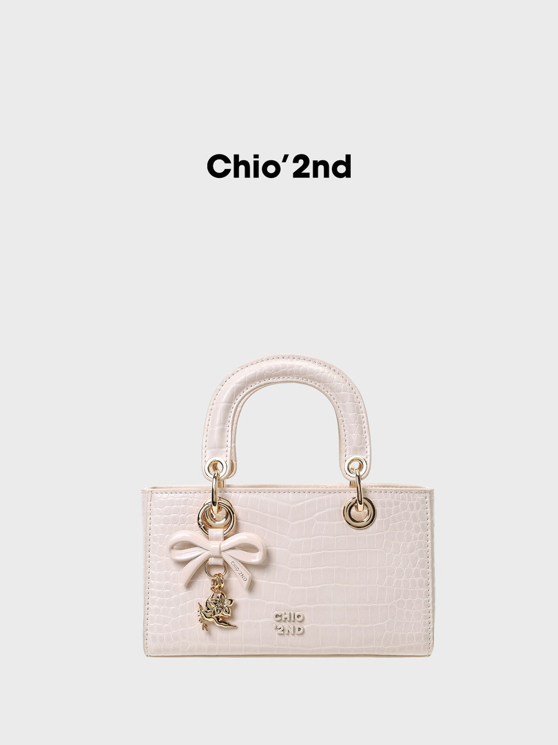 Light beige textured handbag with gold hardware and bow charm