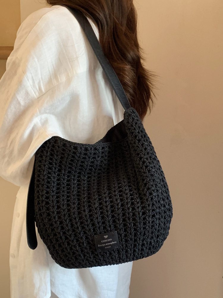 Black woven shoulder bag worn on a model